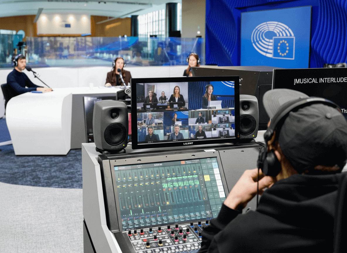 Operador en cabina de control del estudio VoxBox del Parlamento Europeo. Mobiliario técnico Proasur con mesa de mezclas y pantallas para teleconferencia.