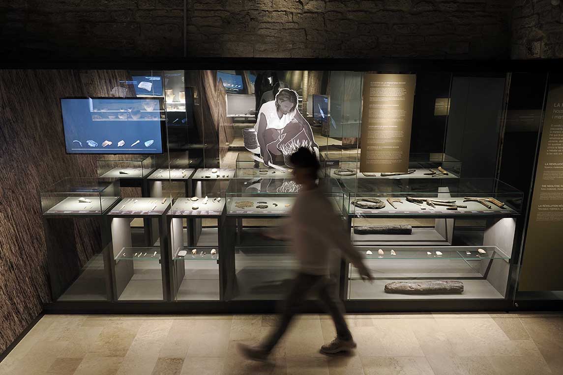 Vitrinas con herramientas neolíticas en el Museo Arqueológico Comarcal de Banyoles, con figura recreada de un hombre prehistórico