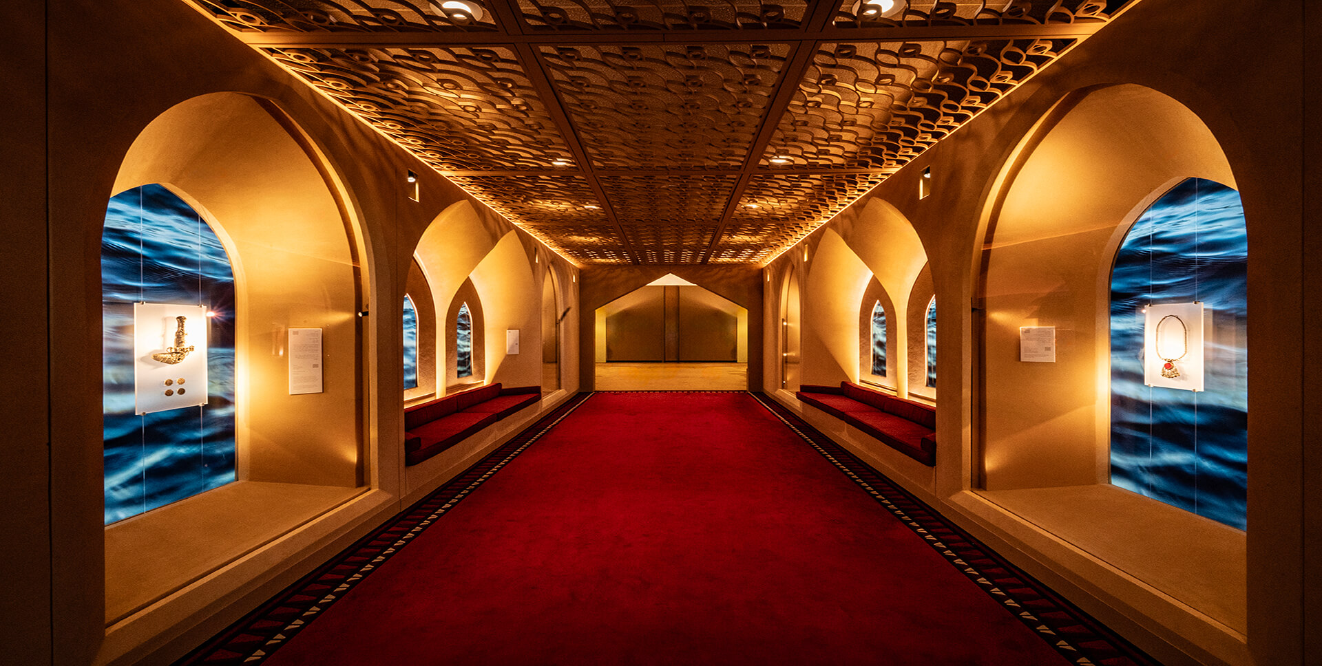 Corredor Omán ONU Nueva York — vista simétrica del pasillo con piezas expuestas en vitrinas y alfombra roja. Producción museográfica de Proasur
