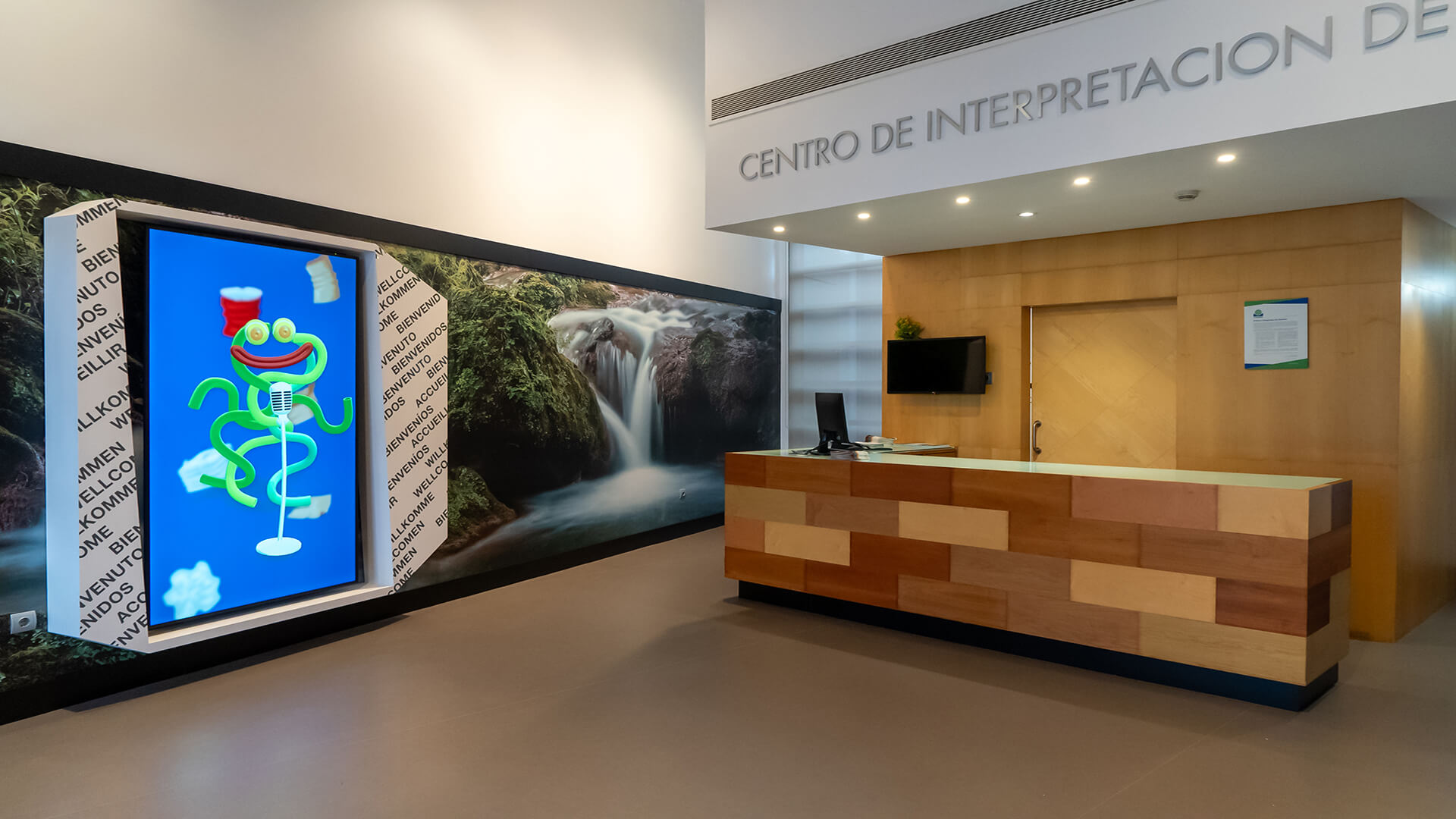 Recepción del Centro de Interpretación de Residuos COGERSA con mostrador de madera y pantalla interactiva